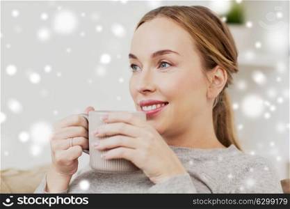 people, drinks and leisure concept - happy woman with cup of tea or coffee drinking at home over snow. happy woman with cup or mug drinking at home