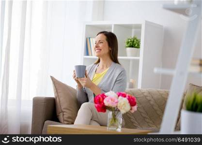 people, drinks and leisure concept - happy woman with mug drinking tea or coffee at home. happy woman drinking tea or coffee at home. happy woman drinking tea or coffee at home