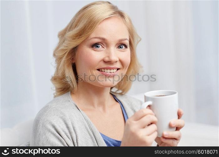 people, drinks and leisure concept - smiling woman with cup of tea or coffee at home