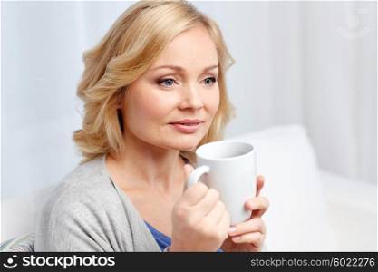 people, drinks and leisure concept - smiling woman with cup of tea or coffee at home