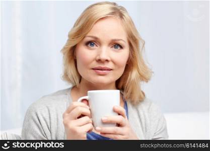 people, drinks and leisure concept - woman with cup of tea or coffee at home