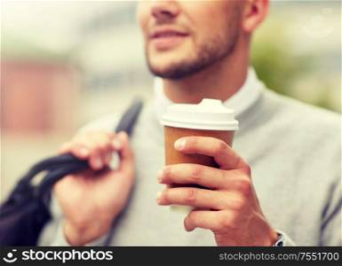 people, drinks and lifestyle - close up of man drinking coffee from disposable paper cup on city street. close up of man with coffee cup on street