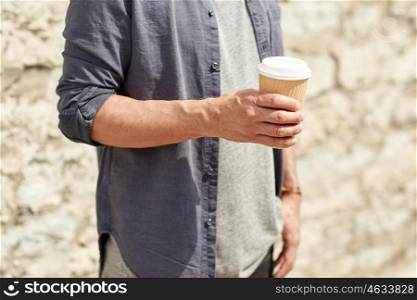 people, drinks, leisure and lifestyle concept - close up of man drinking coffee from disposable paper cup on city street