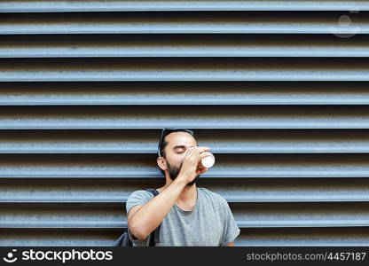 people, drinks, leisure and lifestyle - man drinking coffee from disposable paper cup on city street