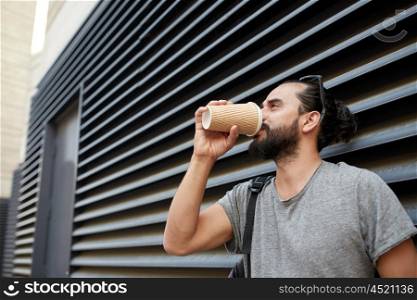 people, drinks, leisure and lifestyle - man drinking coffee from disposable paper cup on city street