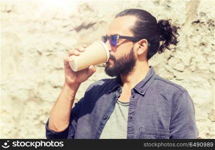 people, drinks, leisure and lifestyle - man drinking coffee from disposable paper cup on city street. man drinking coffee from paper cup on street. man drinking coffee from paper cup on street