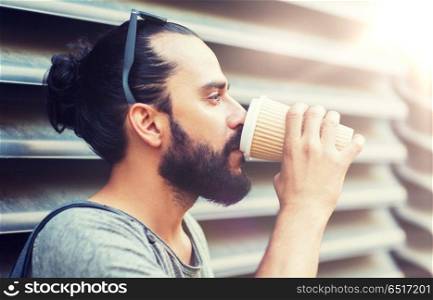 people, drinks, leisure and lifestyle - man drinking coffee from disposable paper cup on city street. man drinking coffee from paper cup on street. man drinking coffee from paper cup on street