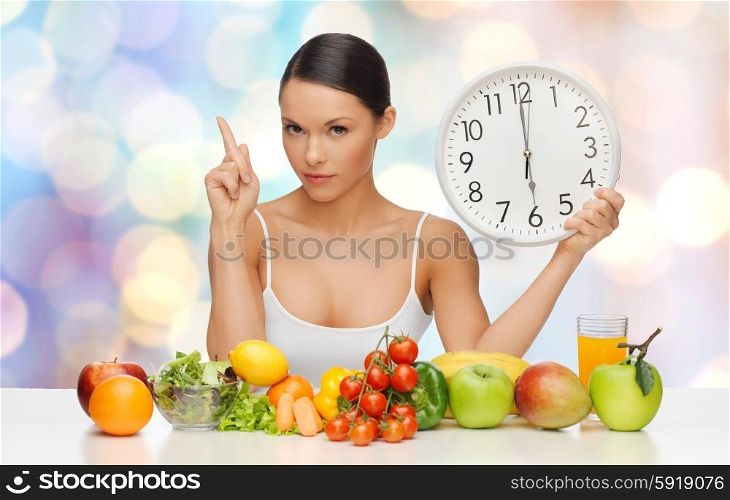 people, eating and diet concept - woman with healthy food holding big clock, pointing finger up and warning over blue lights background