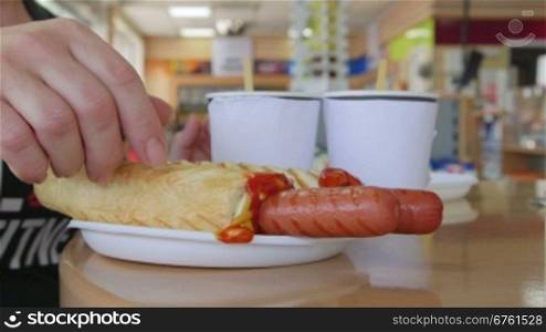 People eating hot dogs with coffee at table in convenience store