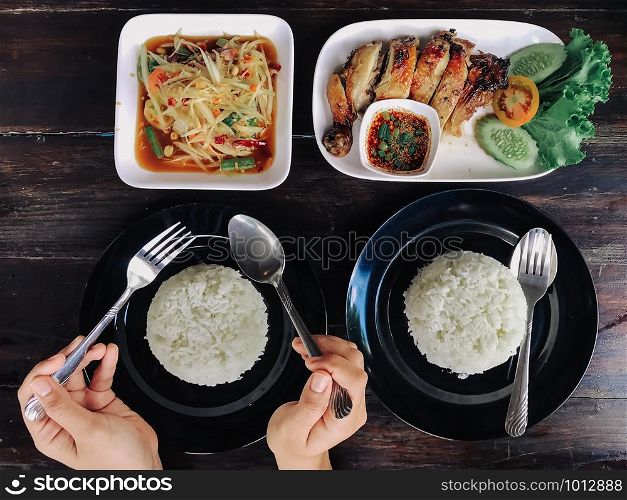 People eating Thai food on a brown wooden table.
