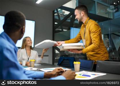 People eats pizza, business lunch in IT office. Professional teamwork and planning, group brainstorming and corporate work, modern company interior on background. People eats pizza, business lunch in IT office