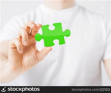 people, ecology and green energy concept - close up of man holding green puzzle piece