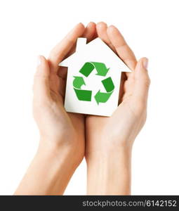 people, ecology, environment and conservation concept - close up of hands holding house with green recycling sign