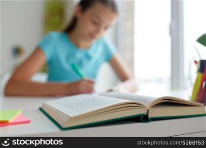 people, education and children concept - girl with book writing at home. girl with book writing at home