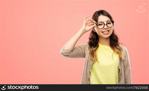 people, education and school concept - happy asian woman or student in glasses fixed by tape over living coral background. happy asian woman in glasses or student