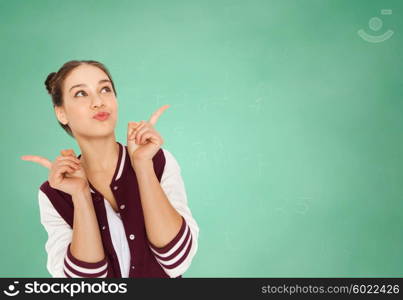 people, education and teens concept - happy pretty teenage student girl with eye makeup over green school chalk board background