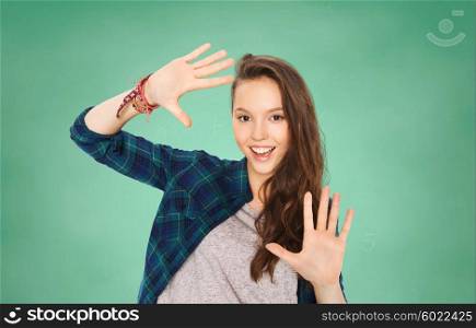 people, education and teens concept - happy smiling pretty teenage student girl showing hands over green school chalk board background