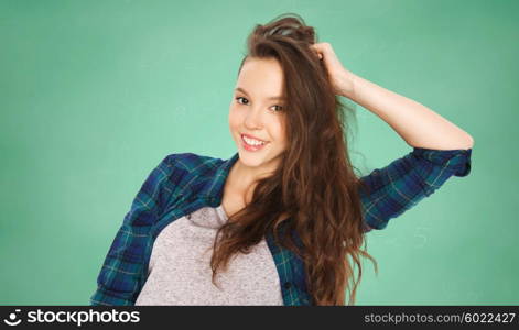 people, education and teens concept - happy smiling pretty teenage student girl touching her head over green school chalk board background over green school chalk board background