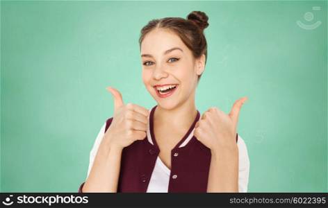 people, education, gesture and teens concept - happy smiling pretty teenage student girl showing thumbs up over green school chalk board background