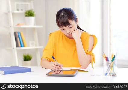 people, education, high school and learning concept - bored asian young woman student with tablet pc computer, book and notepad writing at home