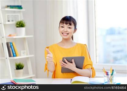 people, education, high school and learning concept - happy asian young woman student with tablet pc computer, book and notepads writing at home