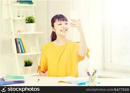 people, education, high school and learning concept - happy asian young woman student taking selfie with smartphone at home. asian woman student taking selfie with smartphone. asian woman student taking selfie with smartphone