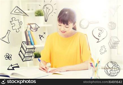 people, education, high school and learning concept - happy asian young woman student with book and notepad writing at home over doodles. happy asian young woman student learning at home. happy asian young woman student learning at home