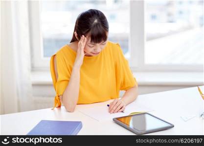 people, education, high school, stress and learning concept - tired asian young woman student with tablet pc computer and notepad suffering from headache at home