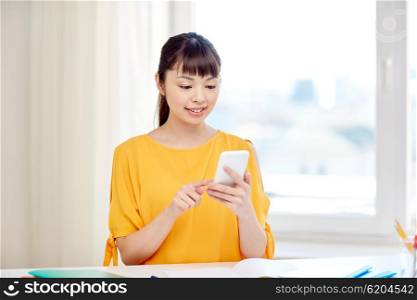 people, education, high school, technology and learning concept - happy asian young woman student with smartphone texting message at home