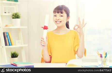 people, education, school, graduation and learning concept - happy asian young woman student with diploma scroll at home showing ok hand sign. happy asian woman student with diploma at home. happy asian woman student with diploma at home