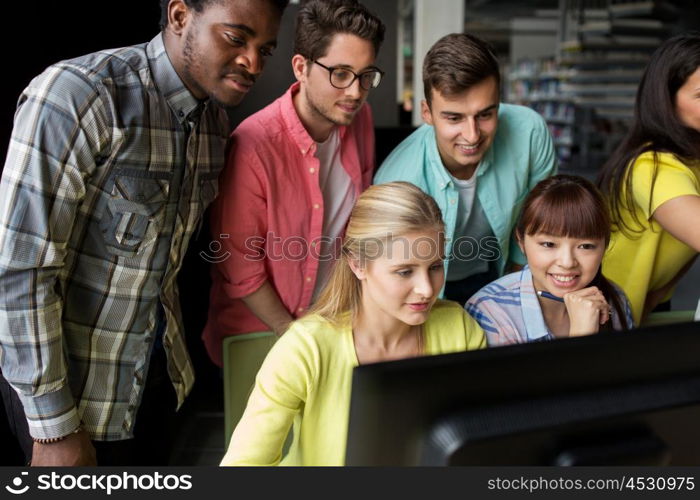 people, education, technology and school concept - group of happy smiling international students with computers at library in university