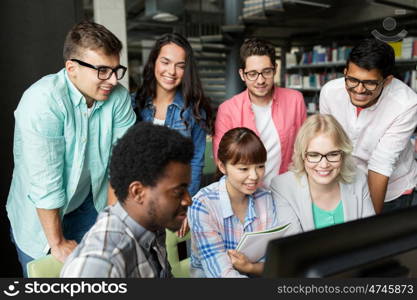 people, education, technology and school concept - group of happy smiling international students with computers at library in university