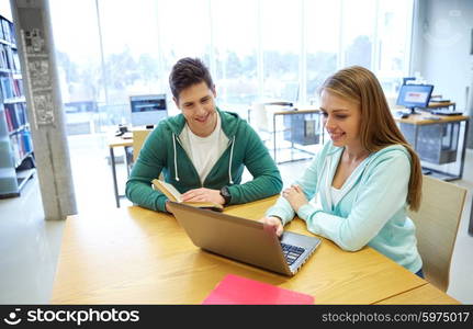 people, education, technology and school concept - happy students with laptop computer and books in library