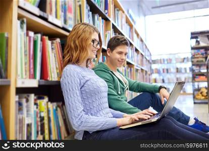 people, education, technology and school concept - happy students with laptop computer networking in library