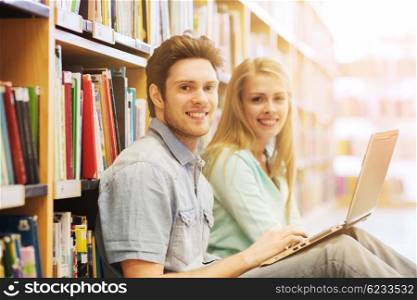 people, education, technology and school concept - happy students with laptop computer networking in library