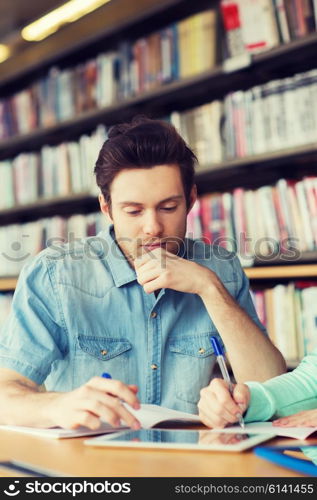 people, education, technology and school concept - male student with tablet pc computer networking in library