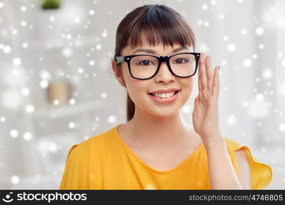 people, education, vision and portrait concept - happy asian young woman or teenage student girl in glasses at home over snow