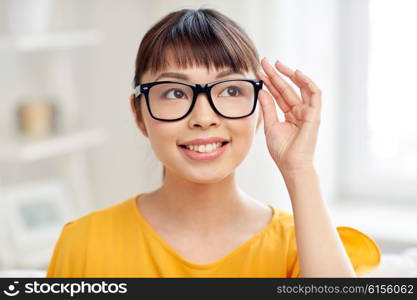 people, education, vision and portrait concept - happy asian young woman or teenage student girl in glasses at home