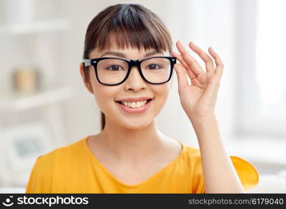 people, education, vision and portrait concept - happy asian young woman or teenage student girl in glasses at home