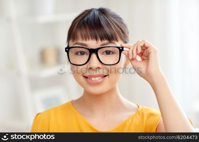 people, education, vision and portrait concept - happy asian young woman or teenage student girl in glasses at home