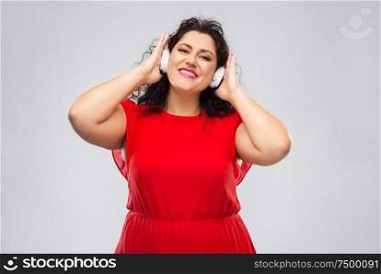 people, electronics and technology concept - happy woman in wireless headphones listening to music over grey background. happy woman in headphones listening to music