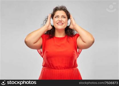 people, electronics and technology concept - happy woman in wireless headphones listening to music over grey background. happy woman in headphones listening to music