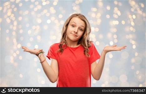 people, emotion and expression concept - wondering teenage girl in red t-shirt shrugging over festive lights background. wondering teenage girl in red t-shirt shrugging