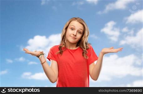people, emotion and expression concept - wondering teenage girl in red t-shirt shrugging over blue sky and clouds background. wondering teenage girl in red t-shirt shrugging