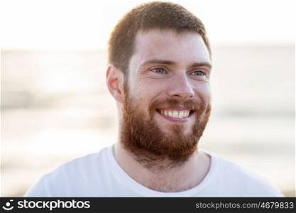 people, emotion and facial expression concept - face of happy smiling young man outdoors