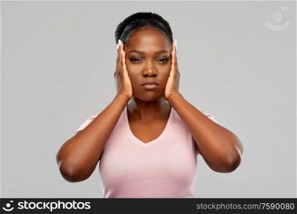 people, emotion and stress concept - screaming african american young woman closing ears by hands over grey background. african american woman closing ears by hands