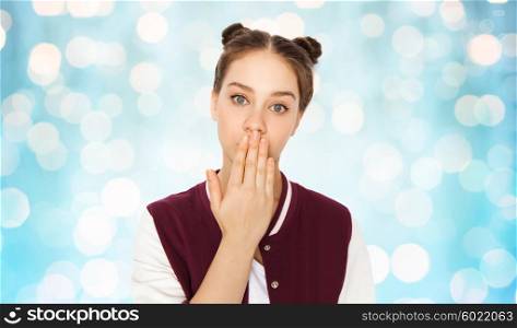 people, emotion, expression and teens concept - confused teenage girl covering her mouth by hand over blue holidays lights background