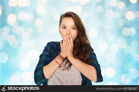 people, emotion, expression and teens concept - scared teenage girl over blue holidays lights background