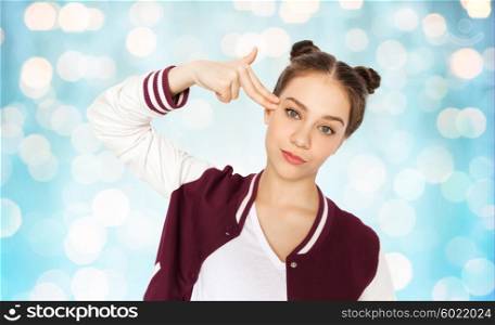 people, emotion, expression, stress and teens concept - bored teenage girl making headshot by finger gun gesture over blue holidays lights background