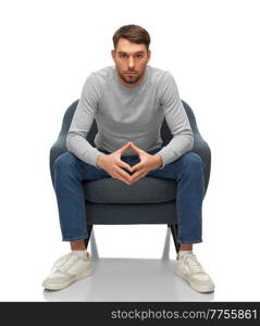 people, emotions and furniture concept - serious man sitting in chair and making triangle of power gesture over white background. man making triangle of power gesture